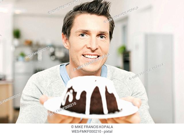 Germany, Cologne, Man holding plate of cake