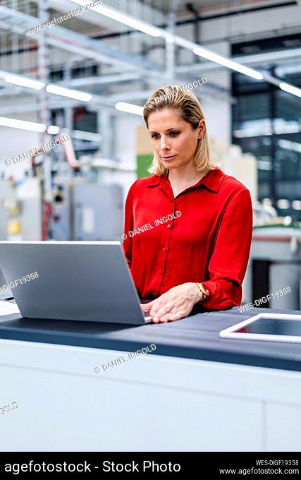Businesswoman working on laptop at factory