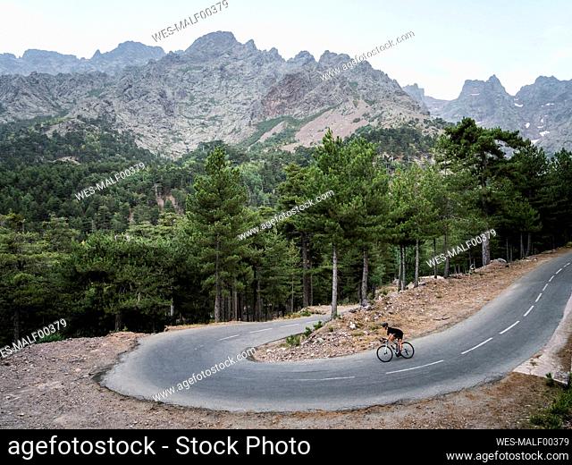 Sportswoman riding mountain bike on winding road