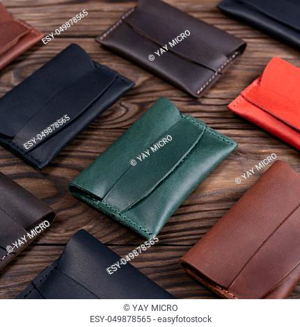 Flat lay photo of five different colour handmade leather one pocket cardholders. Red, black, blown, ginger and green colors