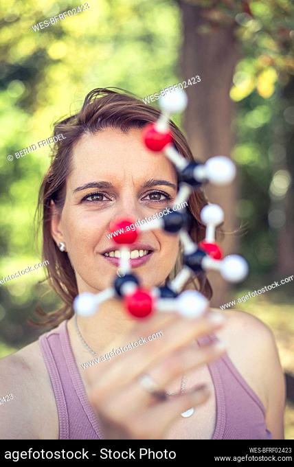 Smiling woman examining molecule model in park