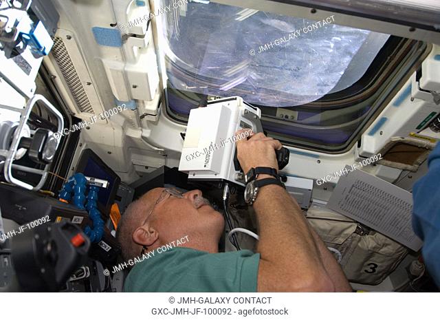 Astronaut John Phillips, STS-119 mission specialist, uses a handheld laser ranging device -- designed to measure the distance between two spacecraft -- through...