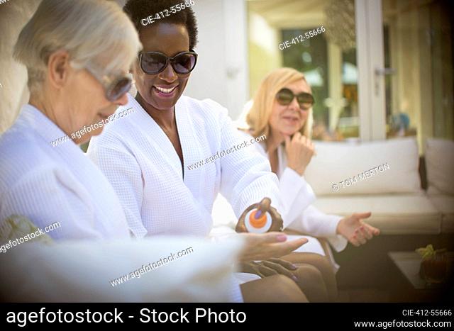 Senior women friends in spa bathrobes and sunglasses on patio