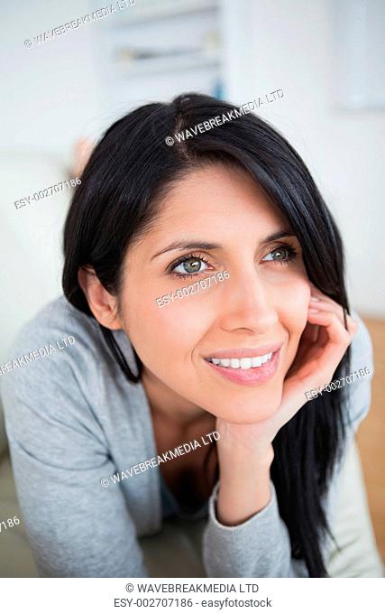 Woman smiling as she holds her head with her palm in a living room