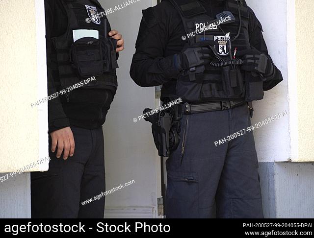 27 May 2020, Berlin: Police officers are standing in front of a house entrance during a raid for dealing with narcotics. Photo: Paul Zinken/dpa-Zentralbild/dpa