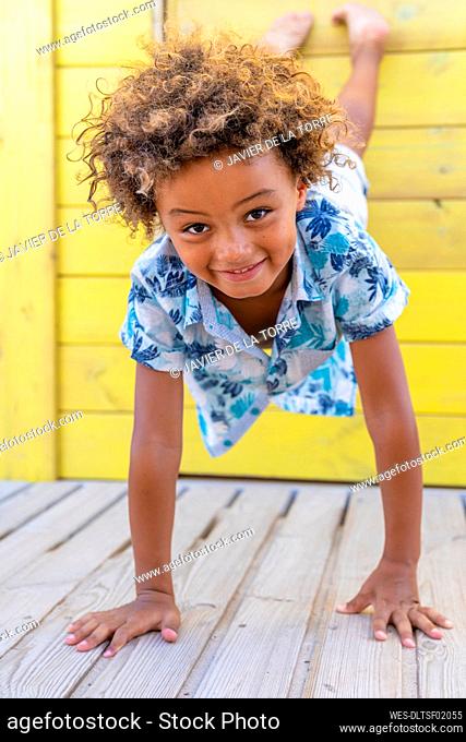 Boy with curly hair balancing on floor with hands