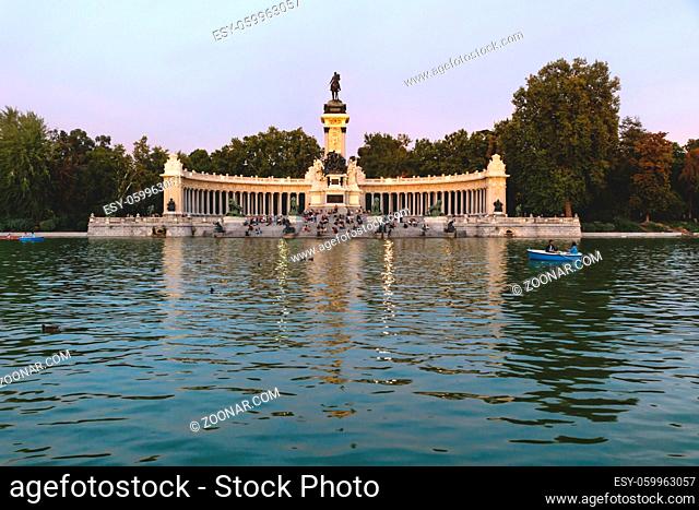 Boats at the lake at the park of Buen Retiro with monument of Alfonso XII King of Spain at sunset, Madrid, Spain