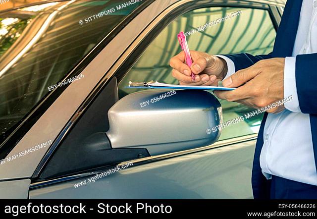 Standing Pose Asian Insurance Agent or Insurance Agency in Suit Write Car Crash Report and Inspecting Car from Accident for Claim at Outdoor Place in Zoom View...