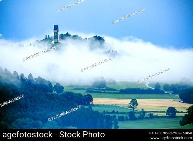 05 July 2023, Baden-Württemberg, Dürmentingen: Fog rolls in after a thunderstorm around the church of St. John Baptist on Mount Bussen in Upper Swabia