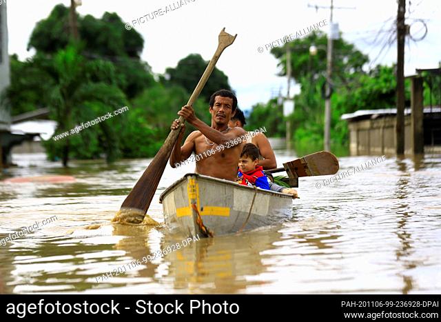 05 November 2020, Honduras, La Lima: A family is canoeing through a flooded road after the low pressure system ""Eta"" caused heavy rainfall throughout the...