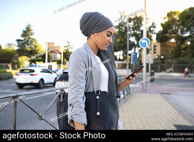 Young woman using smart phone on footpath