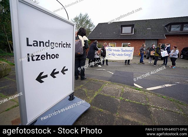 19 October 2021, Schleswig-Holstein, Itzehoe: People holding a banner reading ""Never again fascism! Never again war!"" have gathered next to a signpost reading...