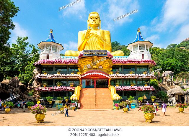 Huge golden Buddha statue on top of the Buddhist Museum of the Golden Temple Dambulla. The holy place is visited from believers, tourists and locals