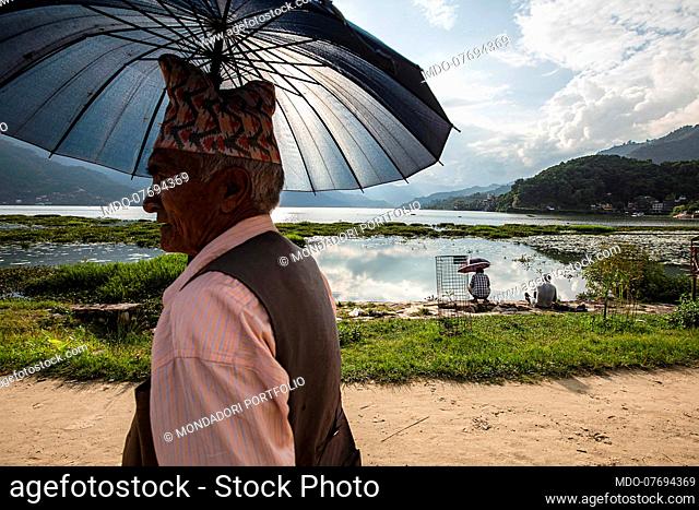 A man with an umbrella protects himself from the sun. Pokhara (Nepal), August 20th 2019