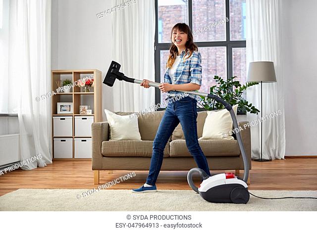 asian woman with vacuum cleaner having fun at home
