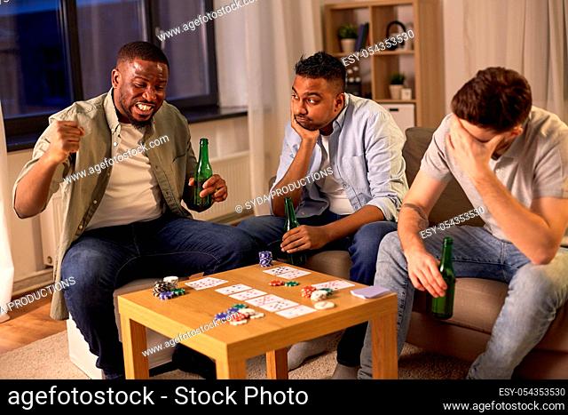male friends playing cards at home at night