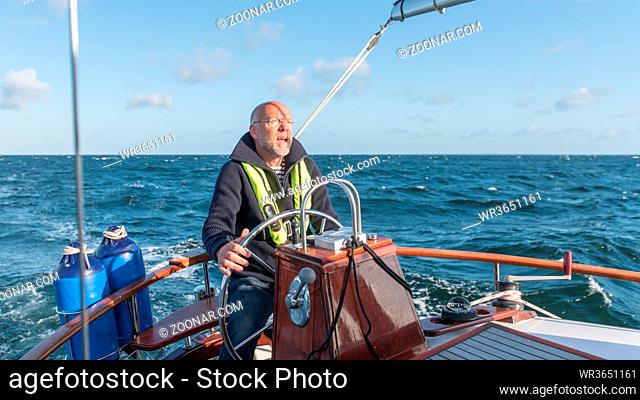 Skipper am Ruder seiner Segelyacht. Skipper controling his sailing boat