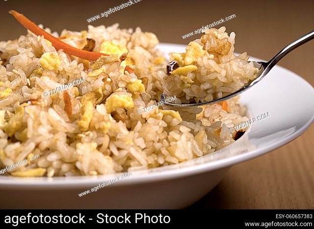 A close up of taking a spoonful of fried rice from a bowl