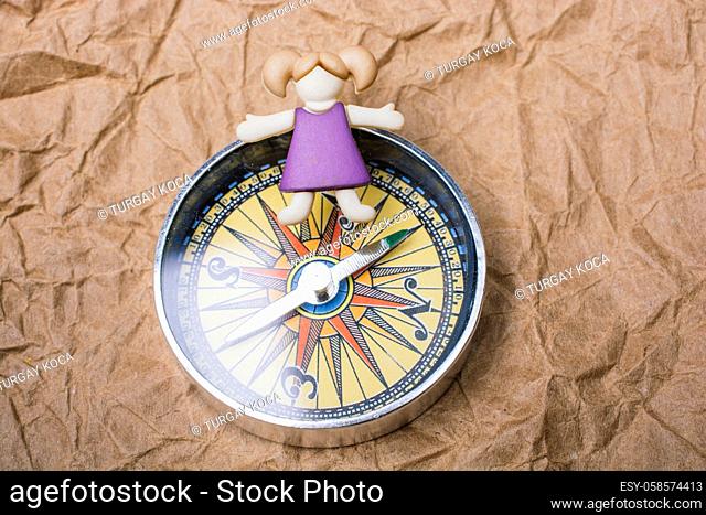 Miniature girl on top of compass as education and business concept