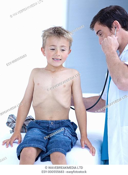 Attractive doctor examinating a little boy with stethoscope