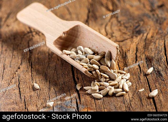 Peeled sunflower seeds with a small wooden shovel on a surface made of old wood