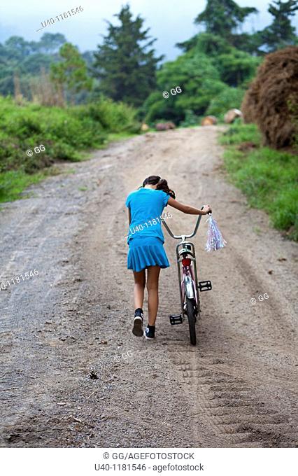 Girl pushing bike up country road