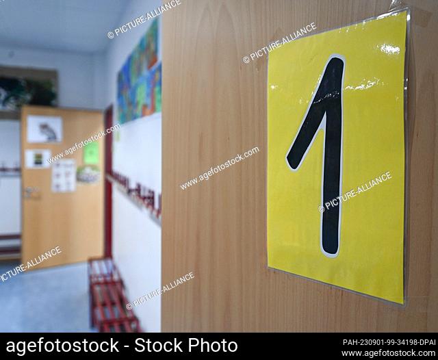 PRODUCTION - 29 August 2023, Hesse, Wiesbaden: A laminated sheet of paper with the number ""1"" is attached to the door of a first grade classroom at Robert...