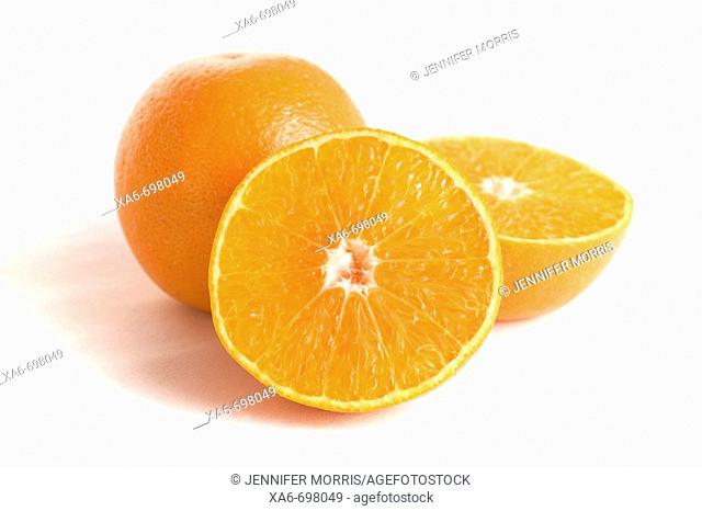 Two oranges, one cut in half, on white background