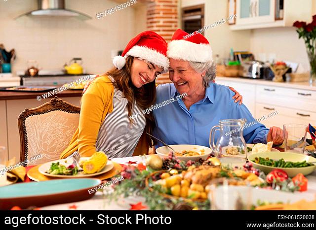 Senior caucasian woman and her adult daughter sitting at table for dinner together