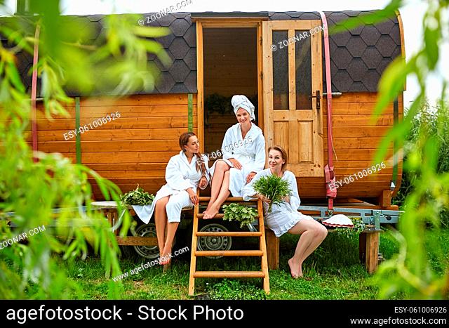 three beautiful young women in towels realxing after wooden sauna. outdoors shot with natural light