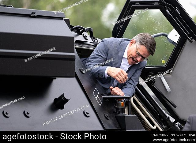 25 July 2023, Hesse, Kassel: Boris Rhein (CDU), Minister President of Hesse, climbs out of the Fuchs tank model during his tour of the Rheinmetall plant