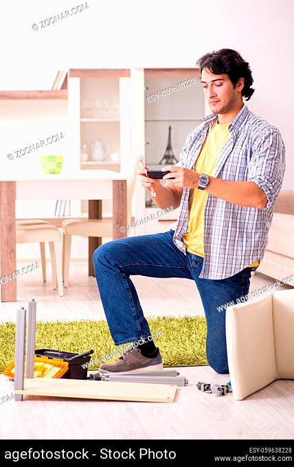 Young handsome man repairing chair at home