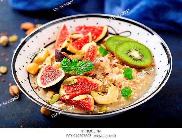 Delicious and healthy oatmeal with figs, nuts, kiwi and seeds. Healthy breakfast. Fitness food. Proper nutrition