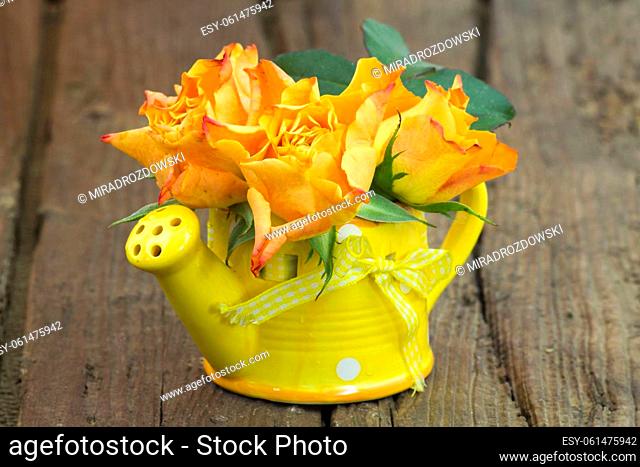 orange roses in a vase - wooden background