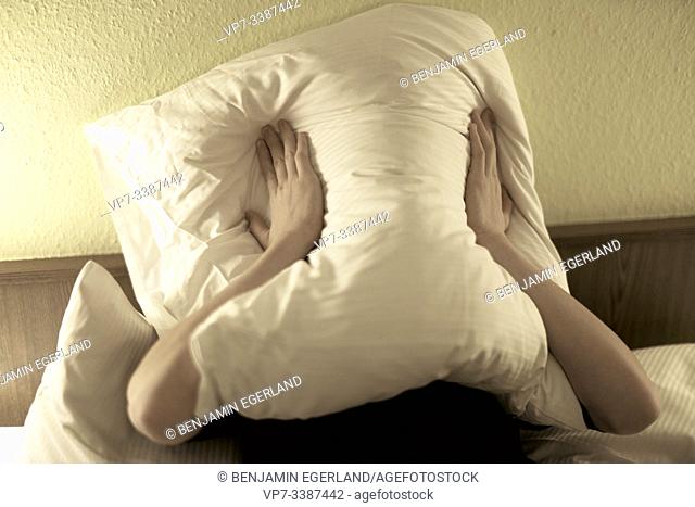 teenager (17 years) pressing pillow on face in bed, depressive, in Germany