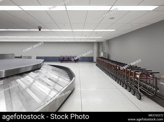 Empty airport luggage claim area, carousels and trolleys