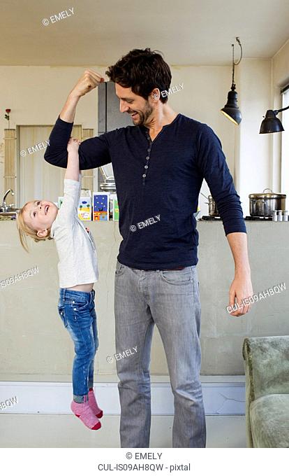 Young girl dangling from her fathers arm