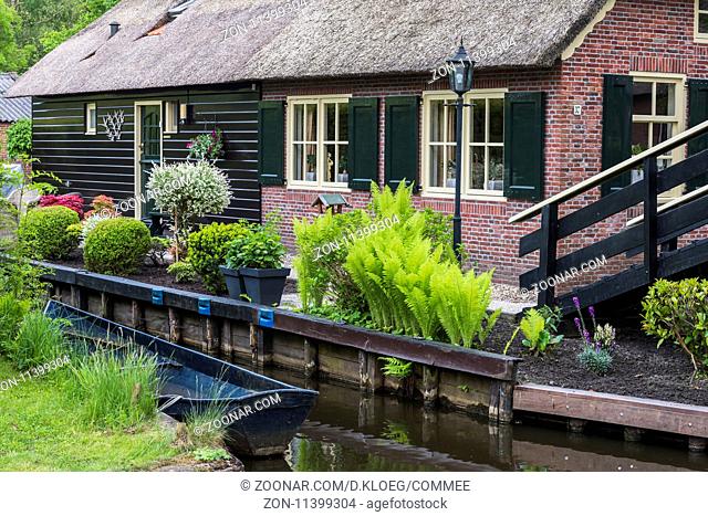 Giethoorn, The Netherlands - May 19., 2016: Front of a monumental house in the small, picturesque town of Giethoorn with canal and rowing boat, Overijssel