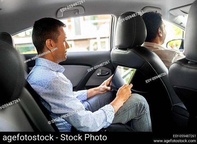 male passenger with tablet computer in taxi car