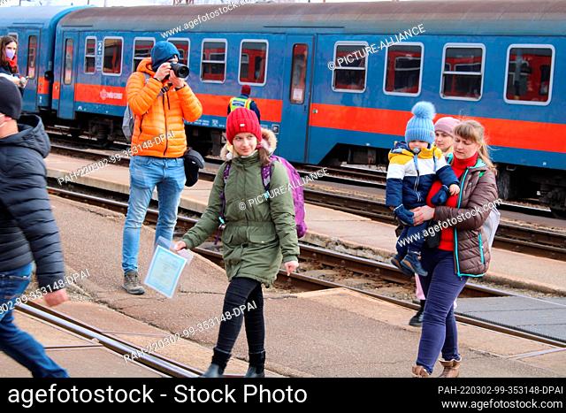 02 March 2022, Hungary, Zahony: Refugees walk across the platform during the arrival of a passenger train with about 800