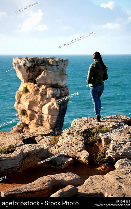 Woman in sea cliffs landscape in Cabo Carvoeiro Cape looking at Berlengas Island, in Peniche, Portugal