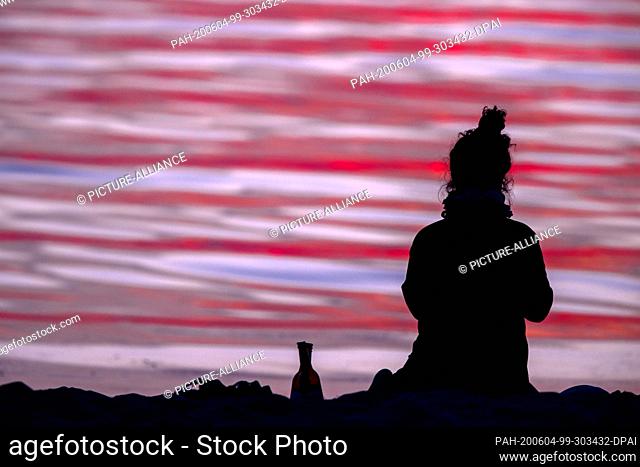 02 June 2020, Mecklenburg-Western Pomerania, Timmendorf (poel): A woman watches the sunset over the Baltic Sea from the beach on the island of Poel