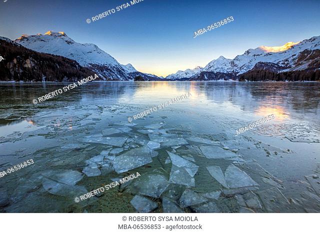 The snowy peaks are reflected on the frozen surface of Lake Sils at dawn Upper Engadine Canton of Graubunden Switzerland Europe