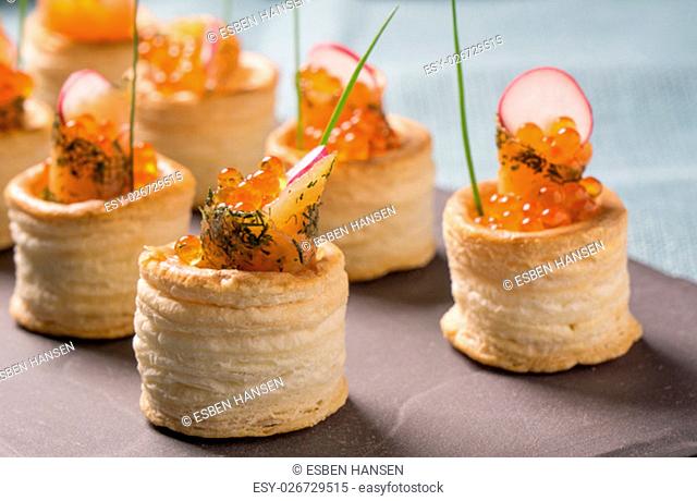 Delicious appetizers with graved salmon and golden caviar served in puff pastry towers