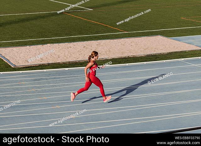 Active sportswoman running on track in stadium