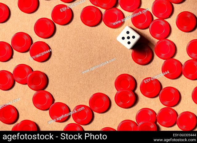 Board games frame with a place for text, top shot of red pieces and a die on a brown background