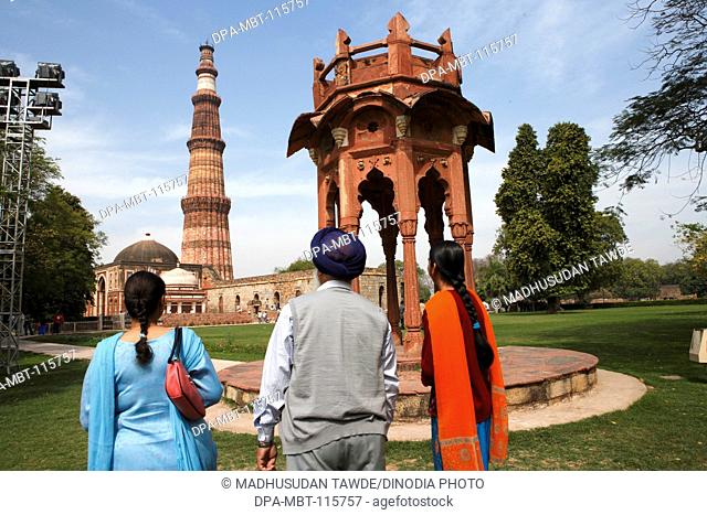 Punjabi Sikh family watching Smith's Folly and Qutb Minar built in 1311 red sandstone tower , Indo-Muslim art , Delhi sultanate , Delhi