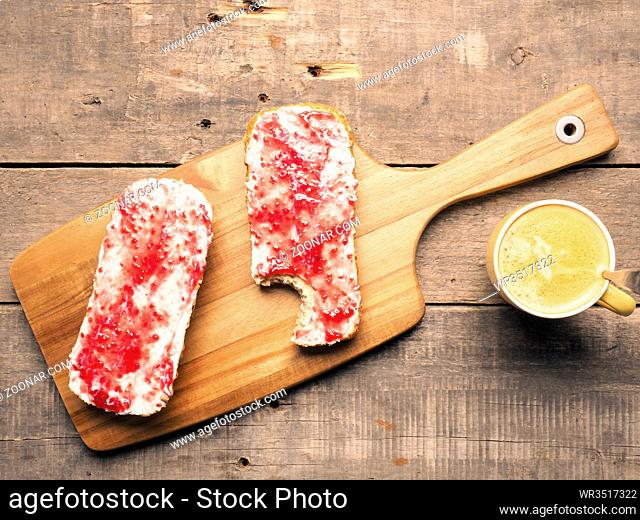 Healthy organic whole grain rolls with sweet and tasty raspberry jam on a wooden cutting board