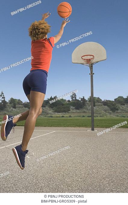 African woman shooting basketball