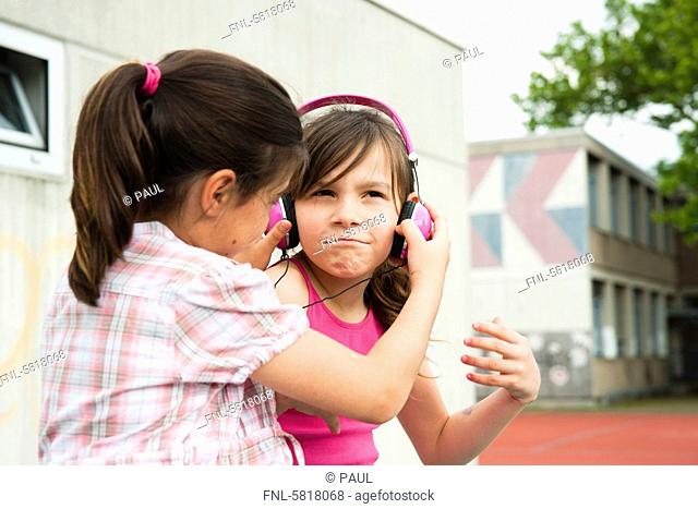 Two girls with headphones on schoolyard